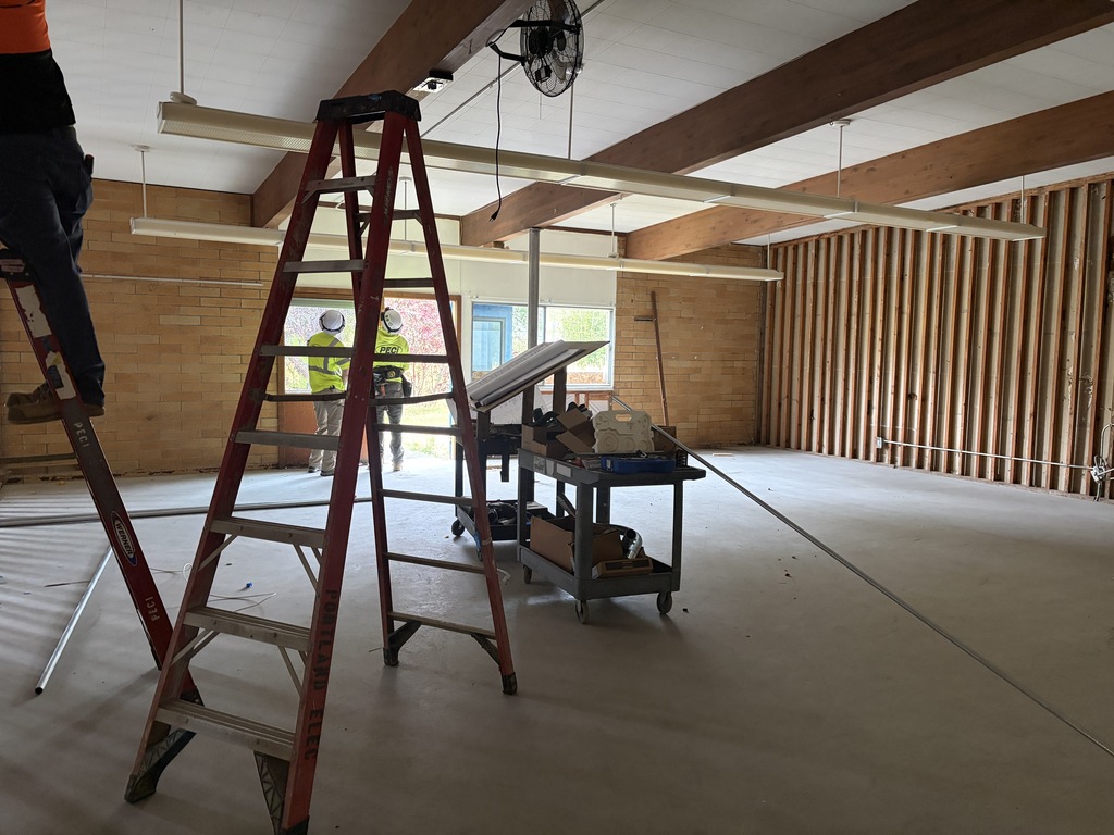 Room under construction with ladder and two people wearing hard hats.