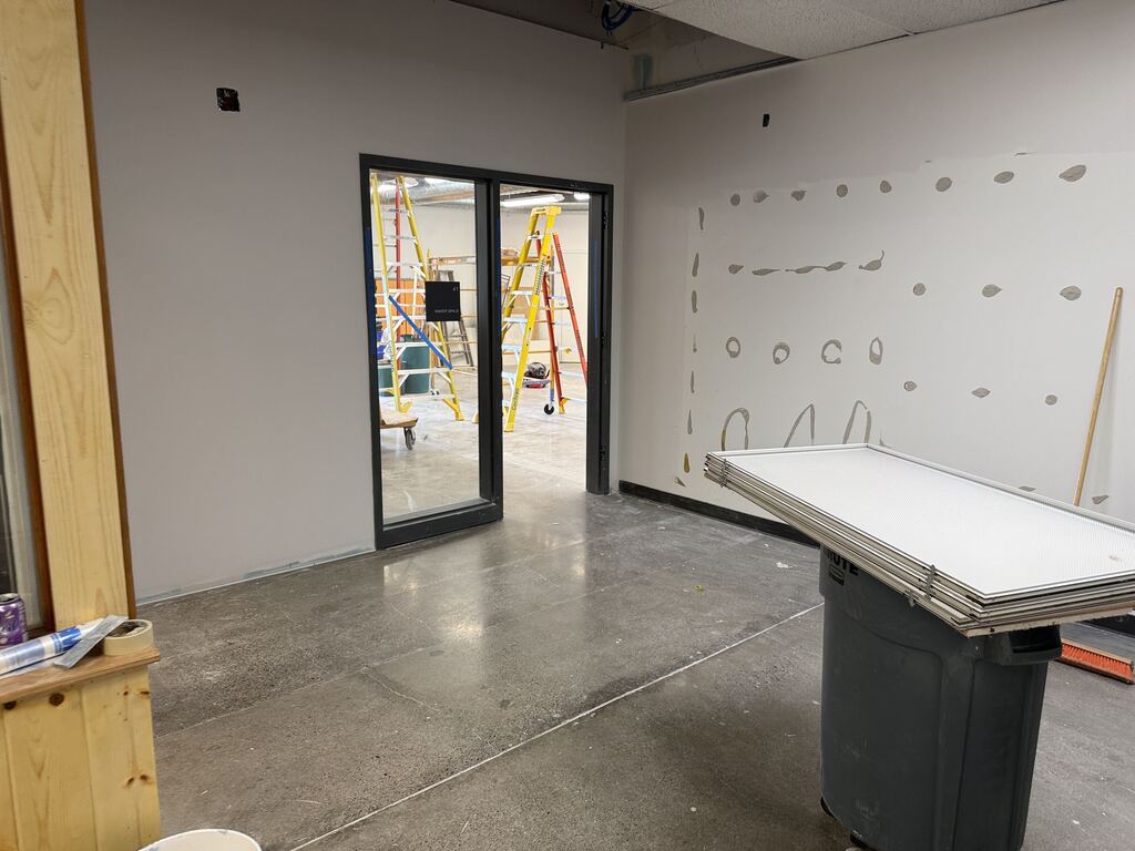 Room under construction with doorway leading into another room with ladders.