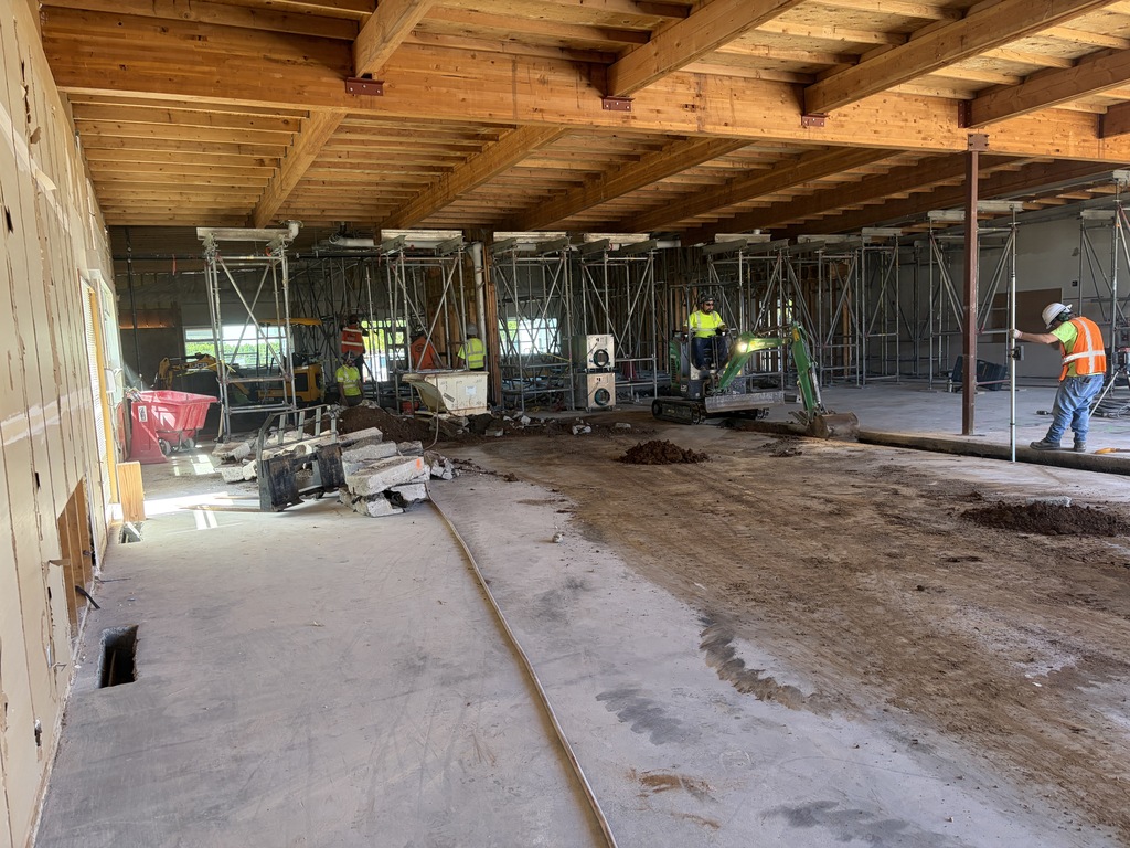 People wearing construction gear working in a room with metal scafollding that is under construction.