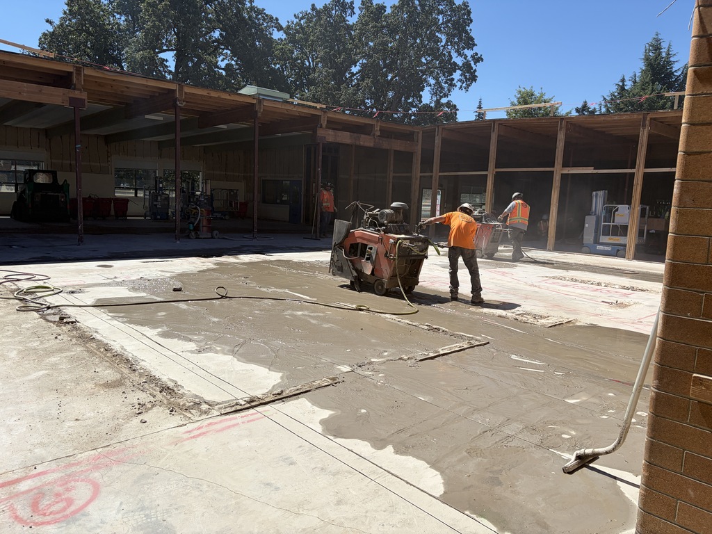 People with construction gear on working in a construction zone where the roof has been removed.
