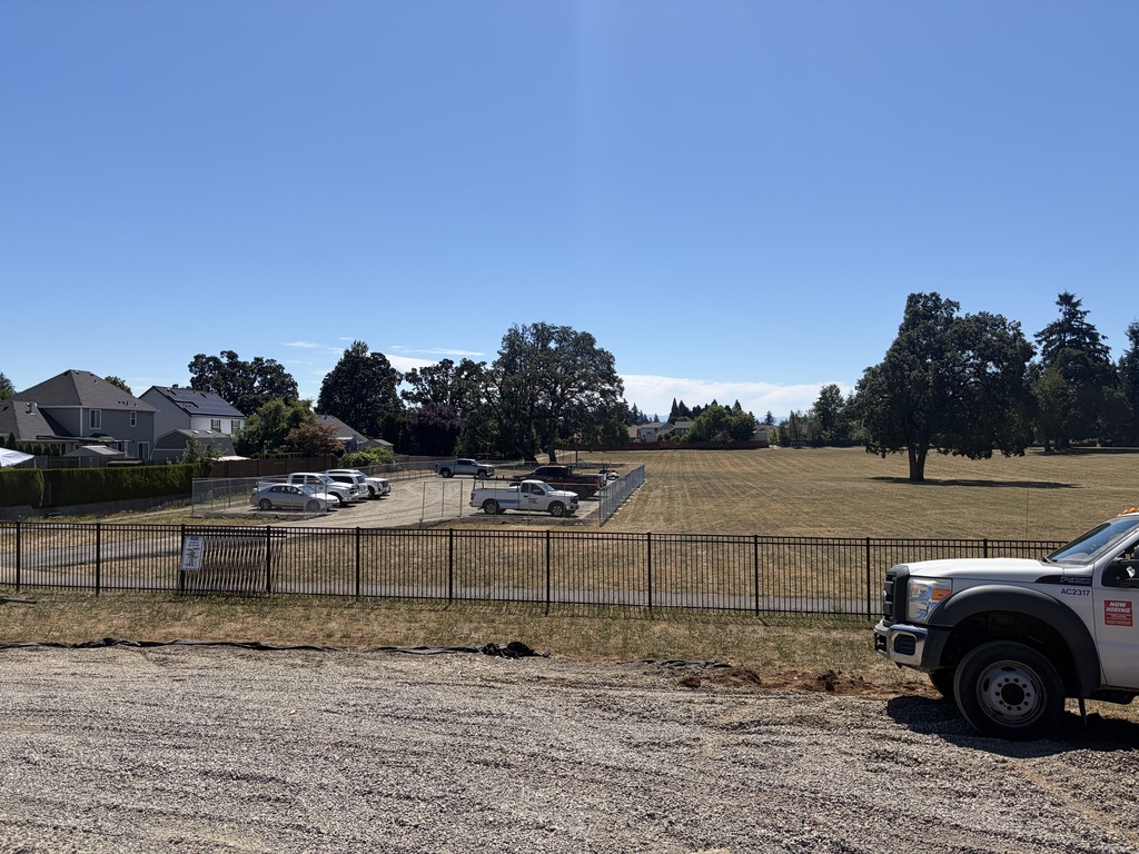 A field with cars parked in it showing wear the constrcution crews park their cars.