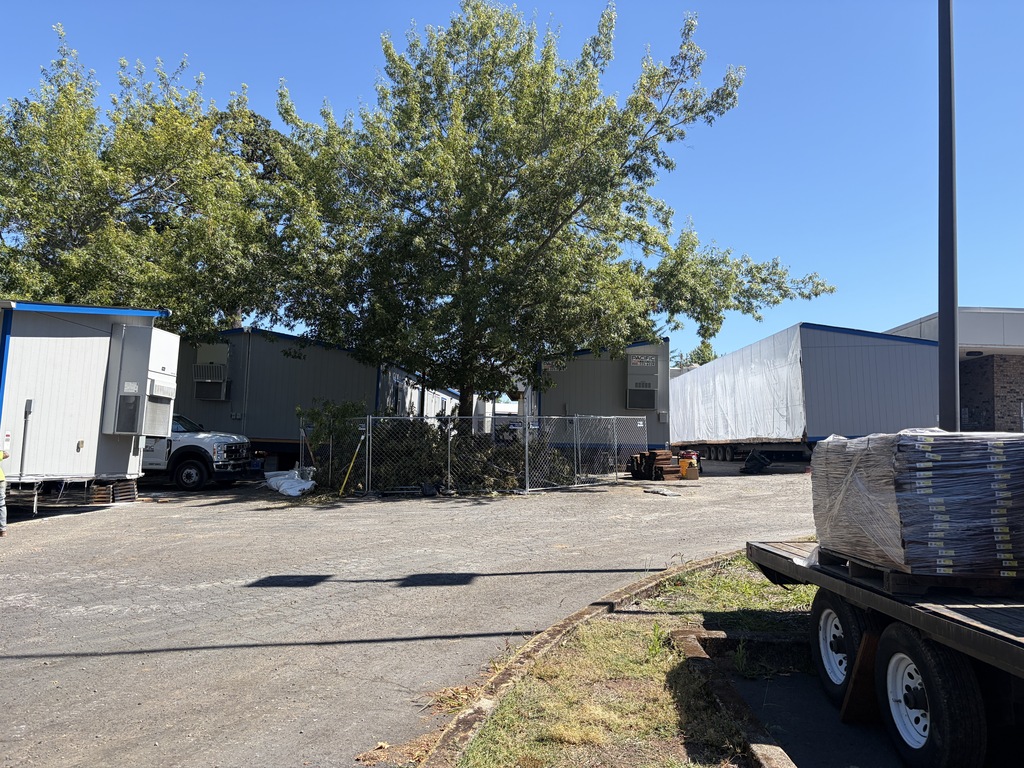 A parking lot with temporary modualrs being staged.