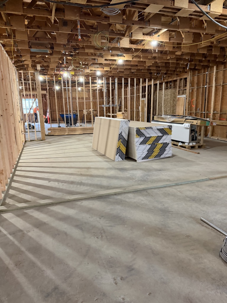 An area under construction with an exposed ceiling and some construction materials in the middle of the room.