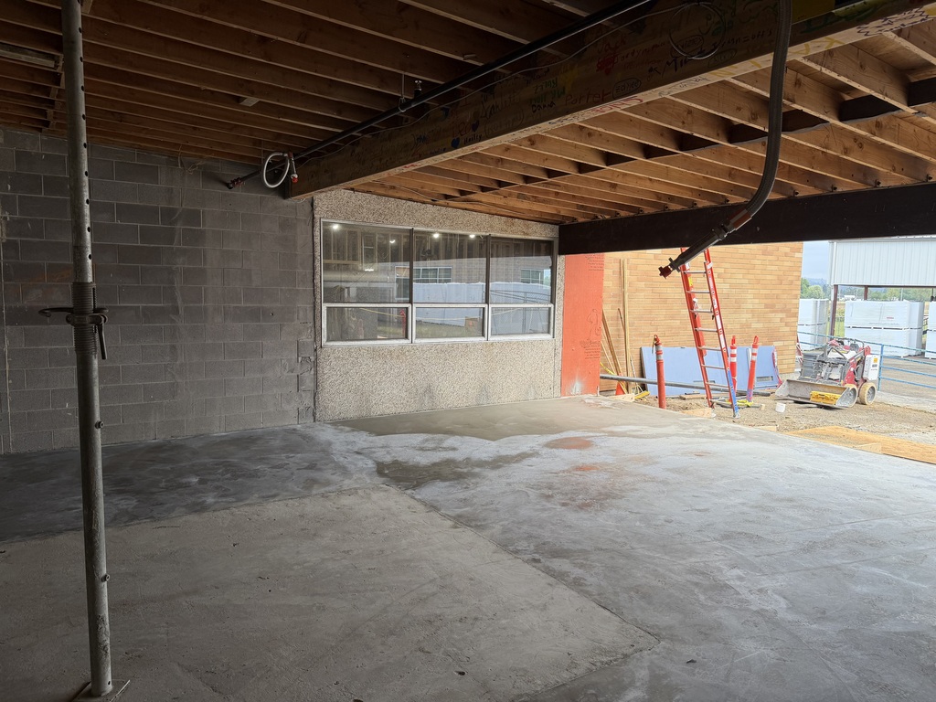 An area under construction with construction equipment and a ladder going onto the roof.