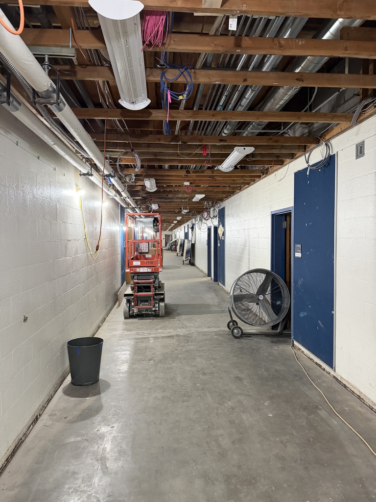 A hallway that is under construction with exposed ceilings.