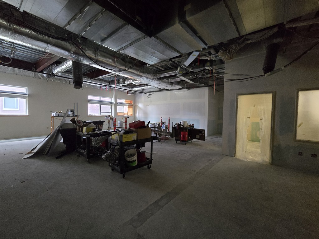 A room under construction showing ceiling ducting and some construction equipment.