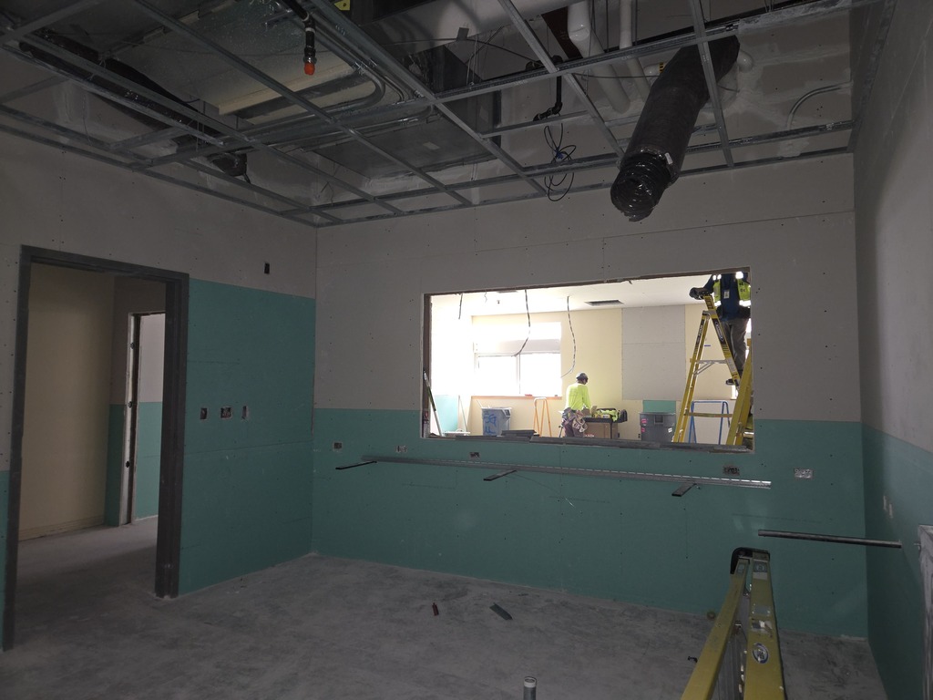 A room under construction showing ceiling ducting and some construction equipment.