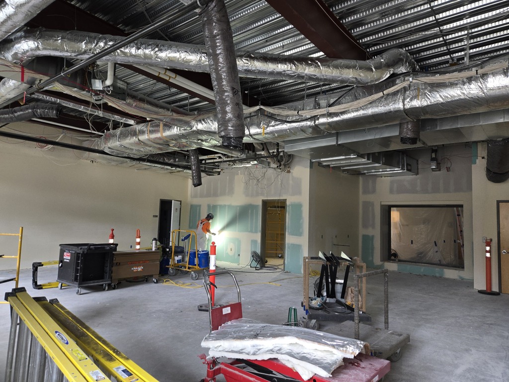 A room under construction showing ceiling ducting and some construction equipment.