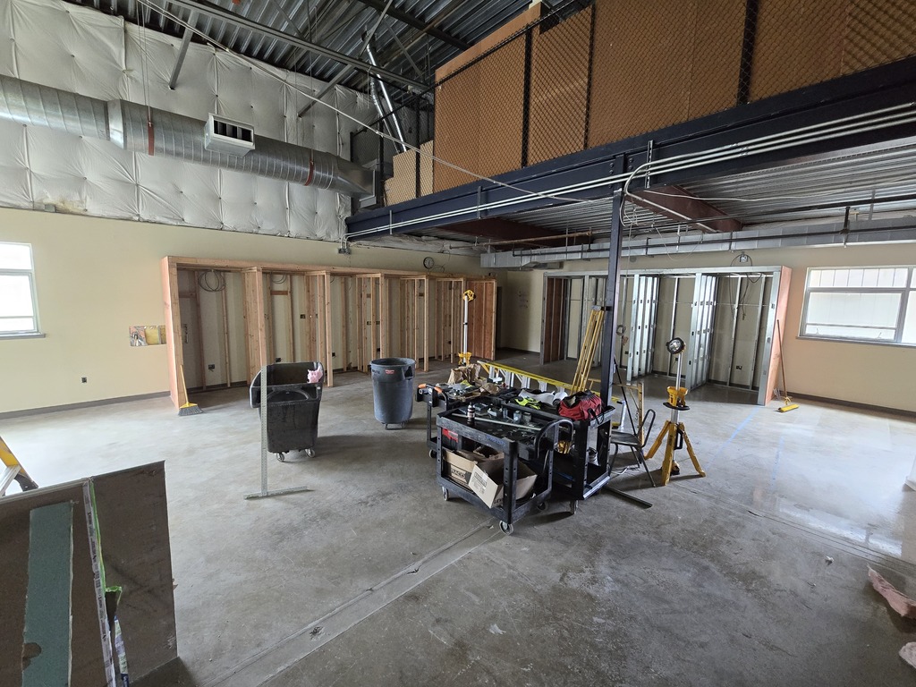 A room under construction with wood framing along the wall and construction equipment.