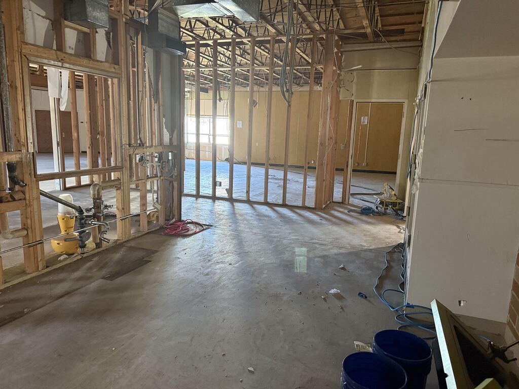 Room under construction with wood framing and construction equipment.