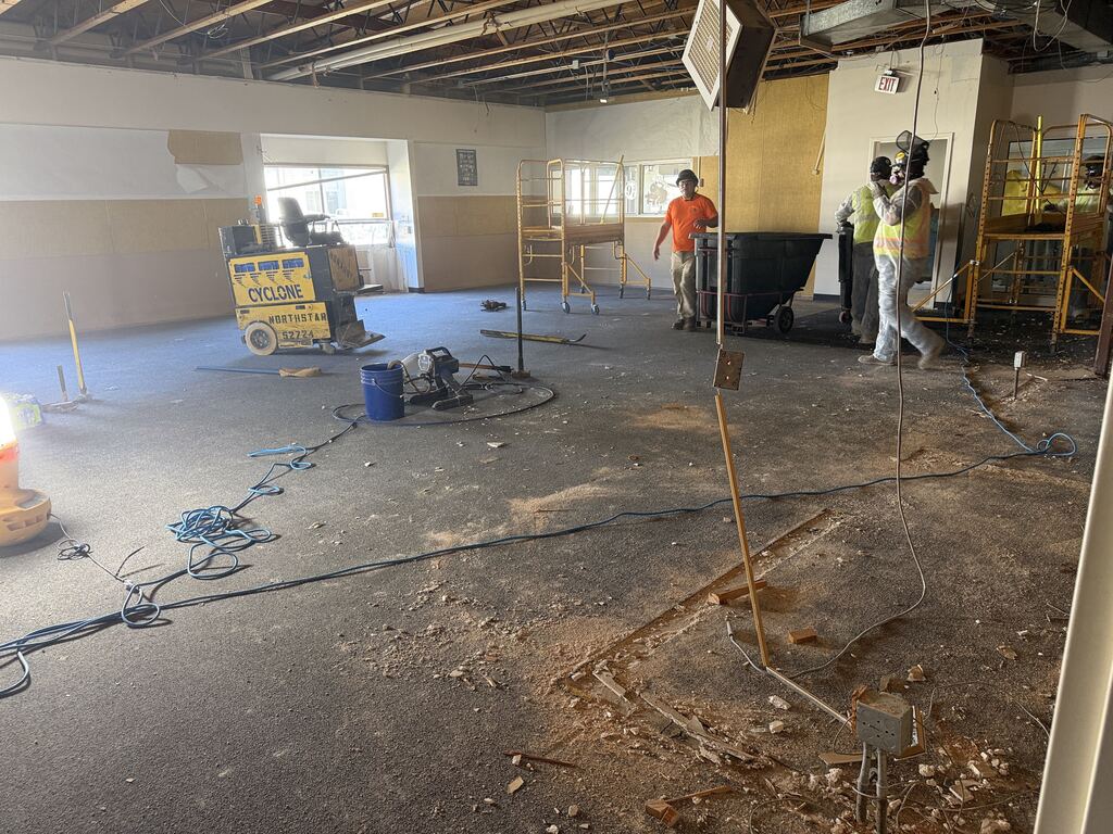Room under construction with three people working and construction equipment.