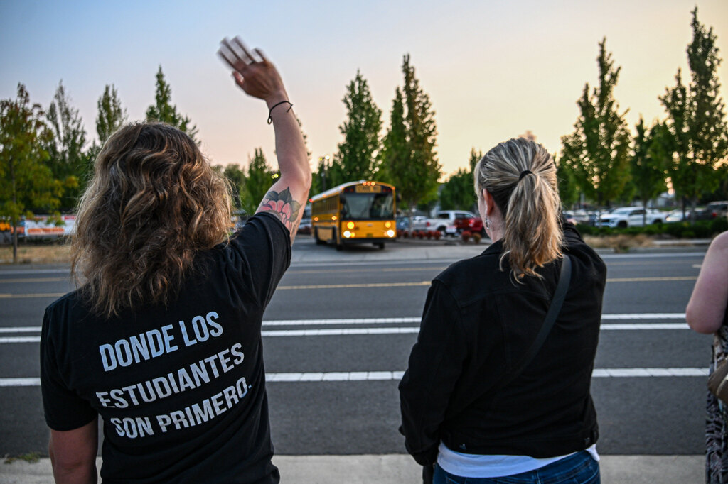 Two oregon city staffers wave to the first bus arriving for school
