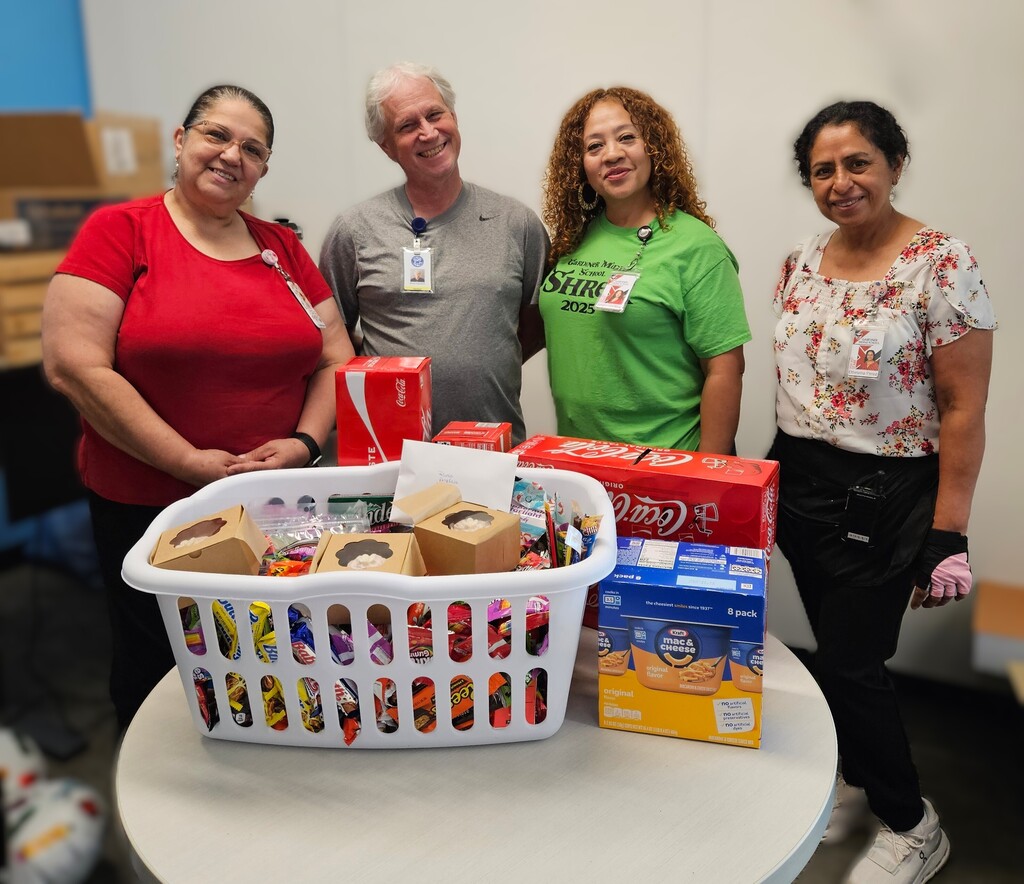Four people standing in front of a table full of snacks