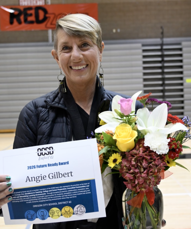 Angie standing with a smile with flowers and award certificate
