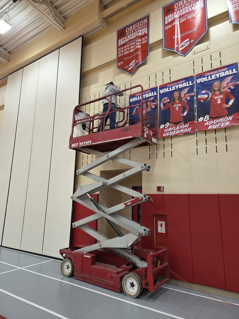 Maintenance worker using scissor lift to hang banners