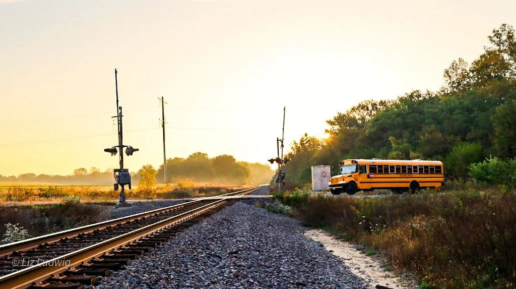 Rising son over bus & rails.