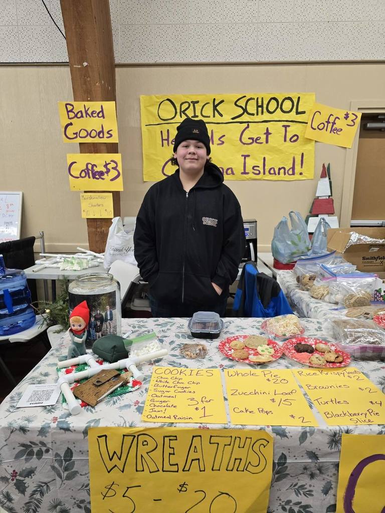 Student standing at table for a bake sale