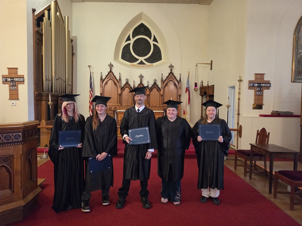 Grads holding diplomas at church