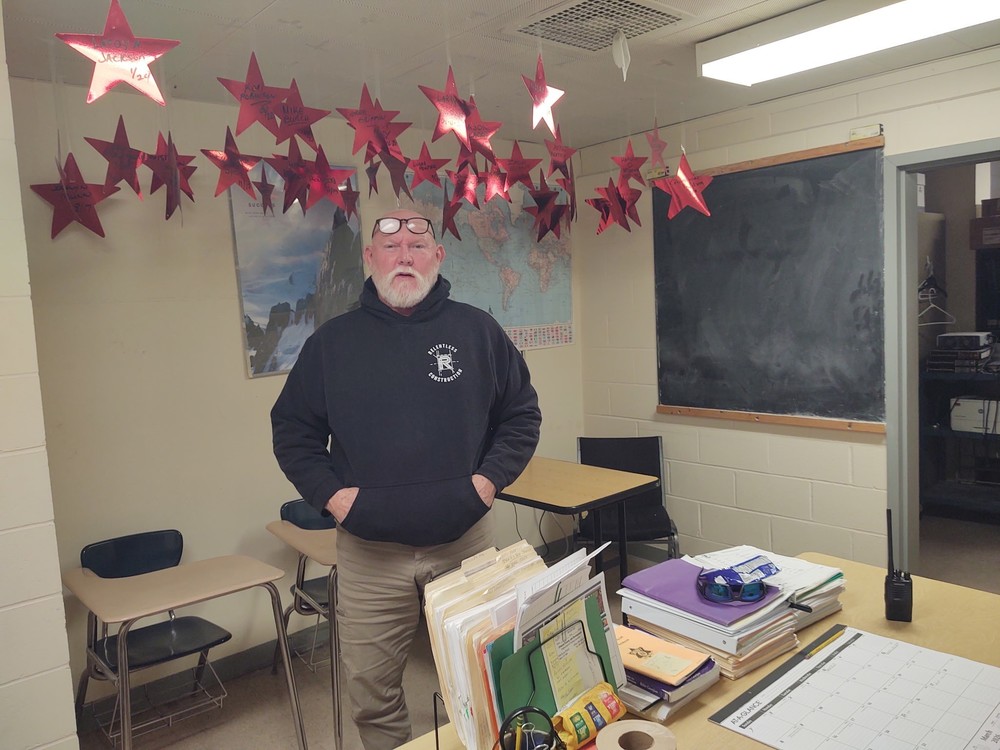 Man standing in classroom with stars hanging from the ceiling