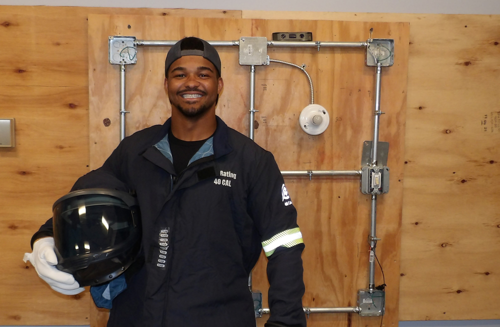 Man holding helmet and standing in front of electrical board