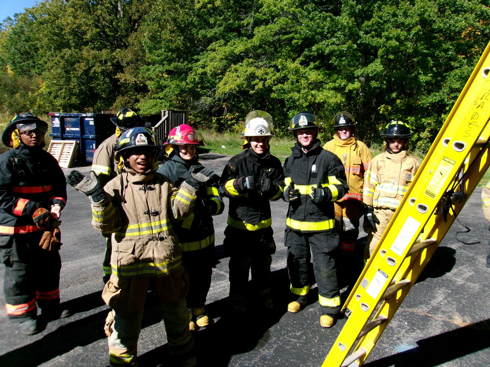 Students in firefighting gear getting ready to climb ladder