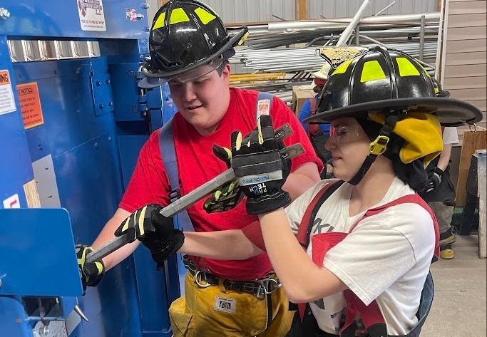 Two students in fire gear trying to open door