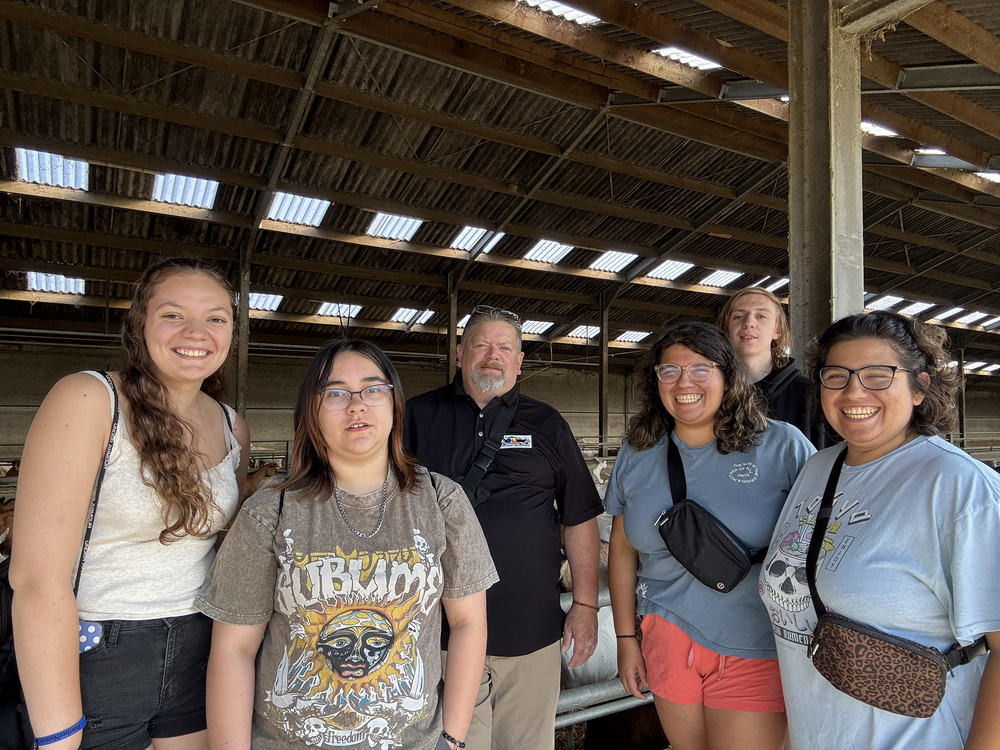 Teacher posing with students in barn