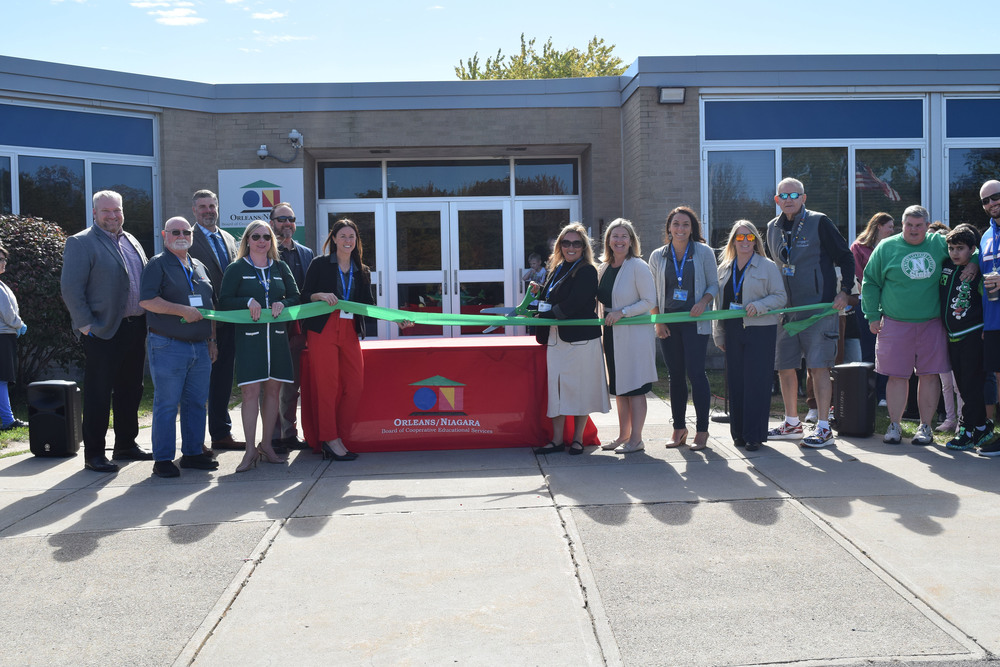 Group of people holding a ribbon across the doorway of building