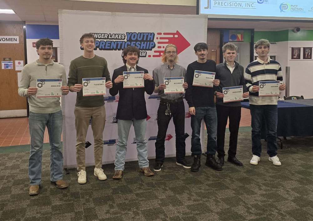 Group of students holding certificates in front of sign