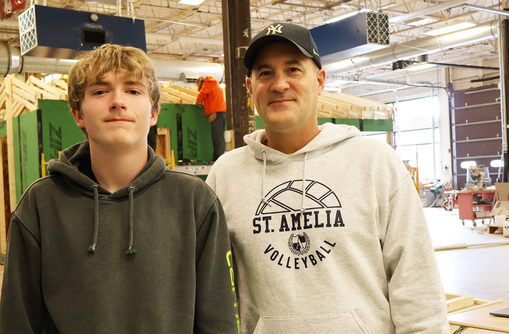 Student posing with teacher in building trades classroom