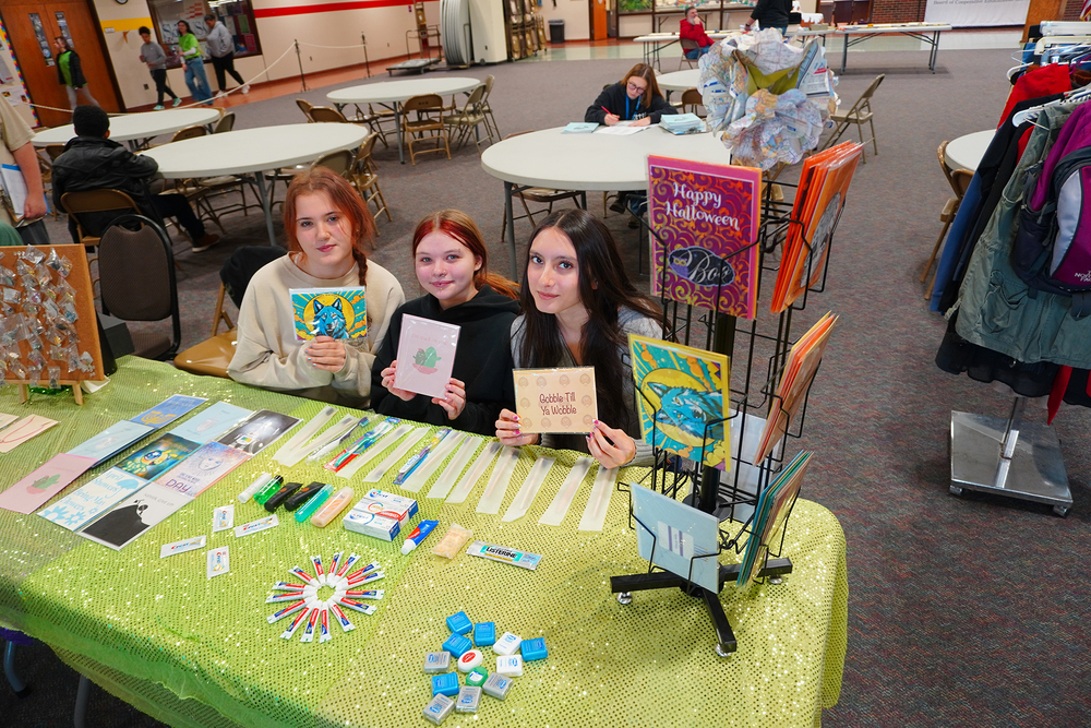 Three students at table with cards and hygiene products