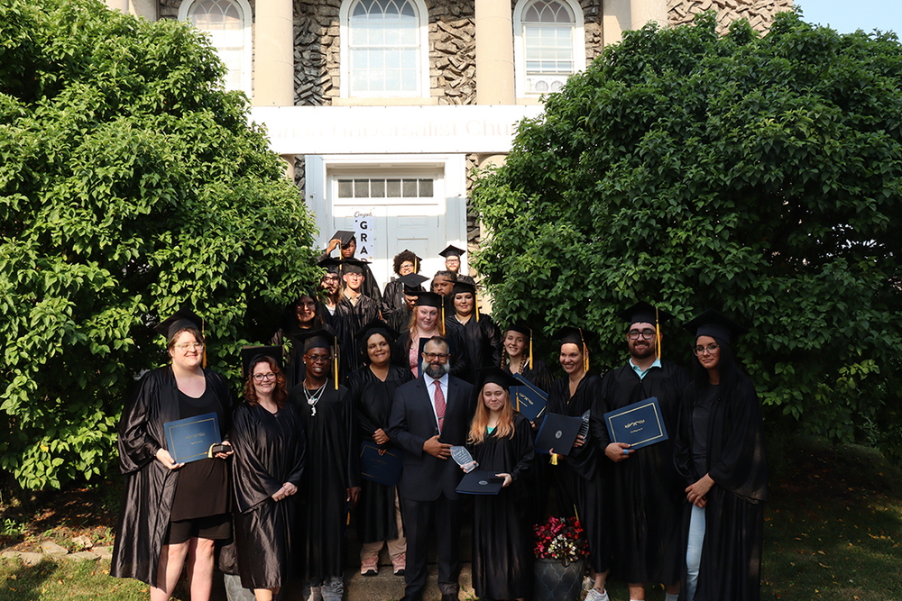 Group pf graduates posing on steps with diplomas