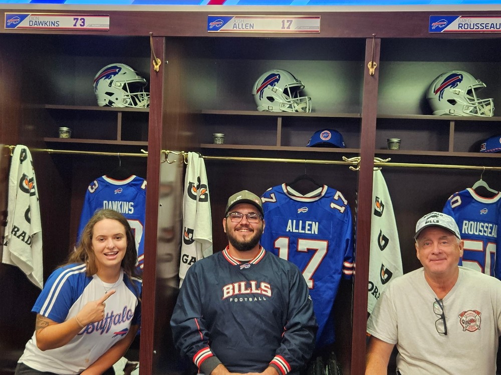 Three people sitting in the Buffalo Bills Locker Room