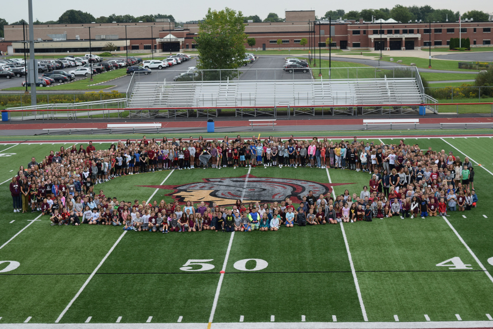 children and teachers standing on a football field around the Starpoint Spartan logo