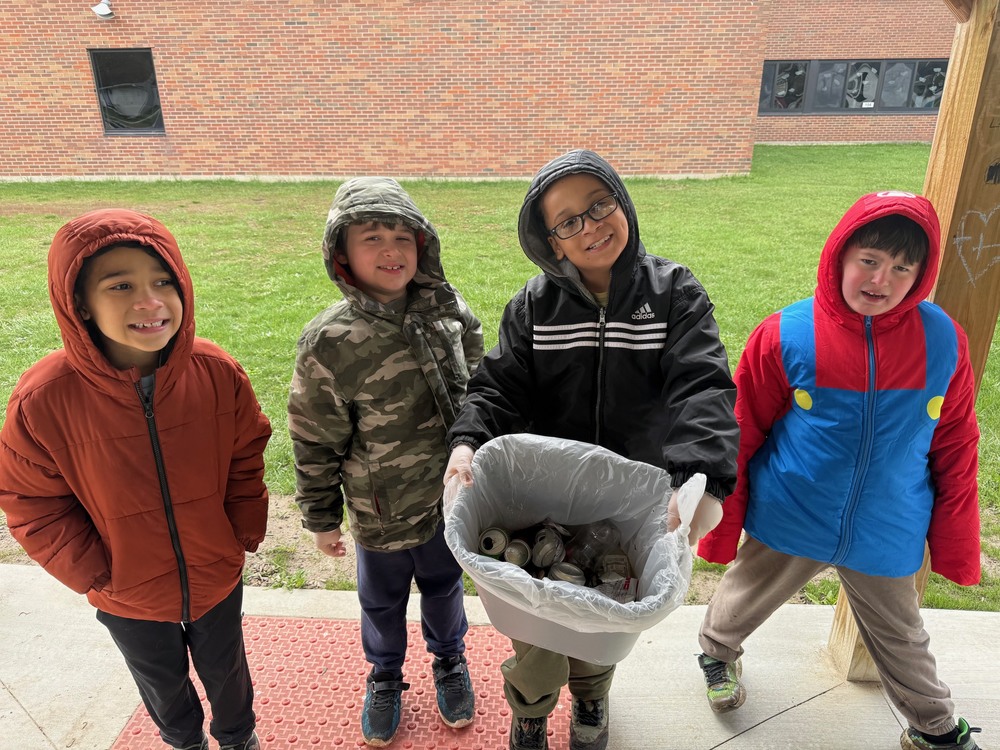 Four students hold bucket with trash