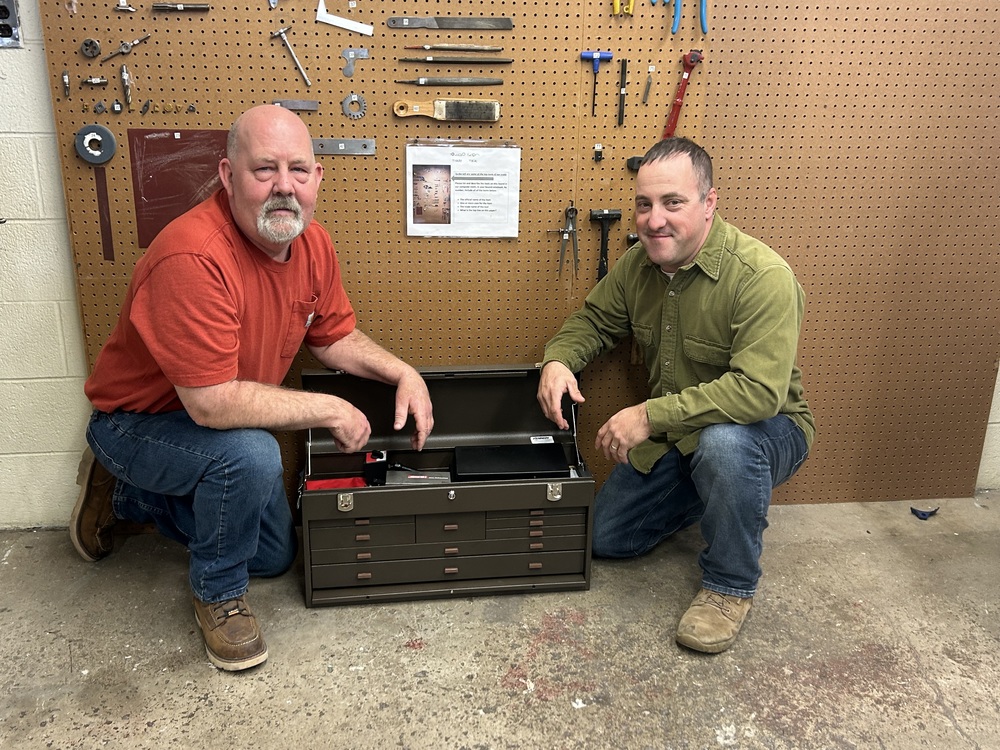 Two men posing next to tool box