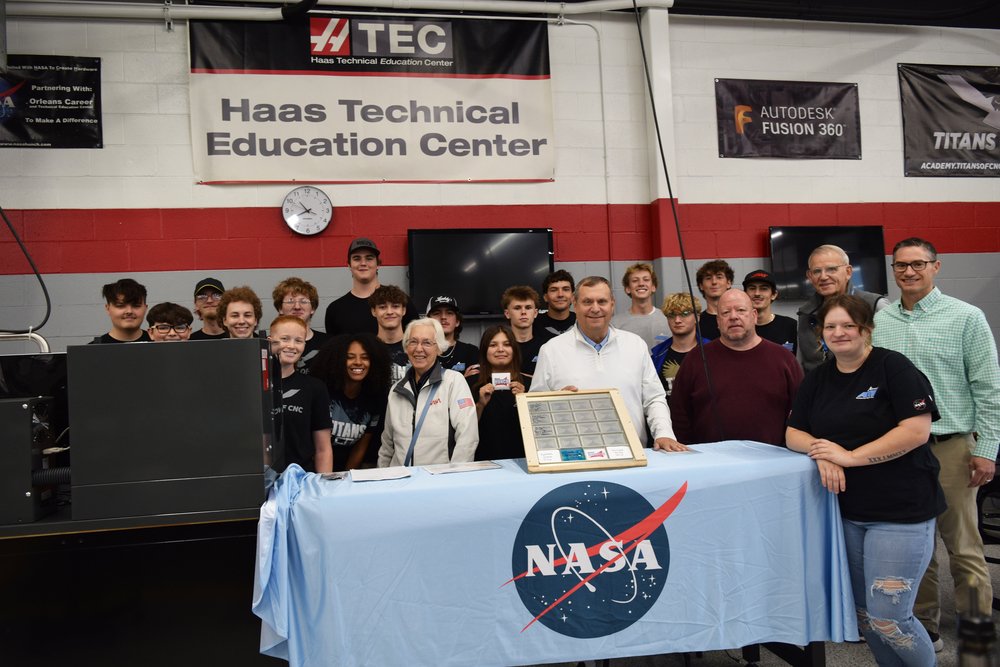 Students and staff pose behind a table with a NASA tablecloth