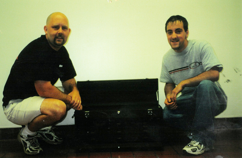 Old photo of two men posing at tool box