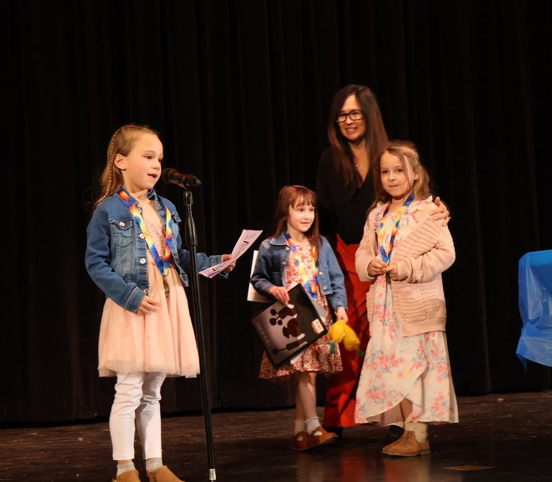 Three students with teacher on stage