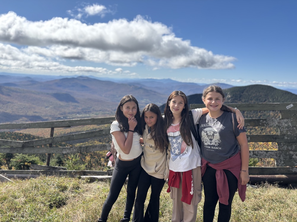 Four girls with arms around shoulders posing at the peak of Jay