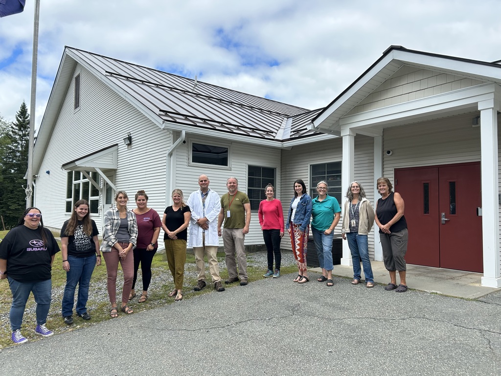 Teachers standing in a line in front of school building 