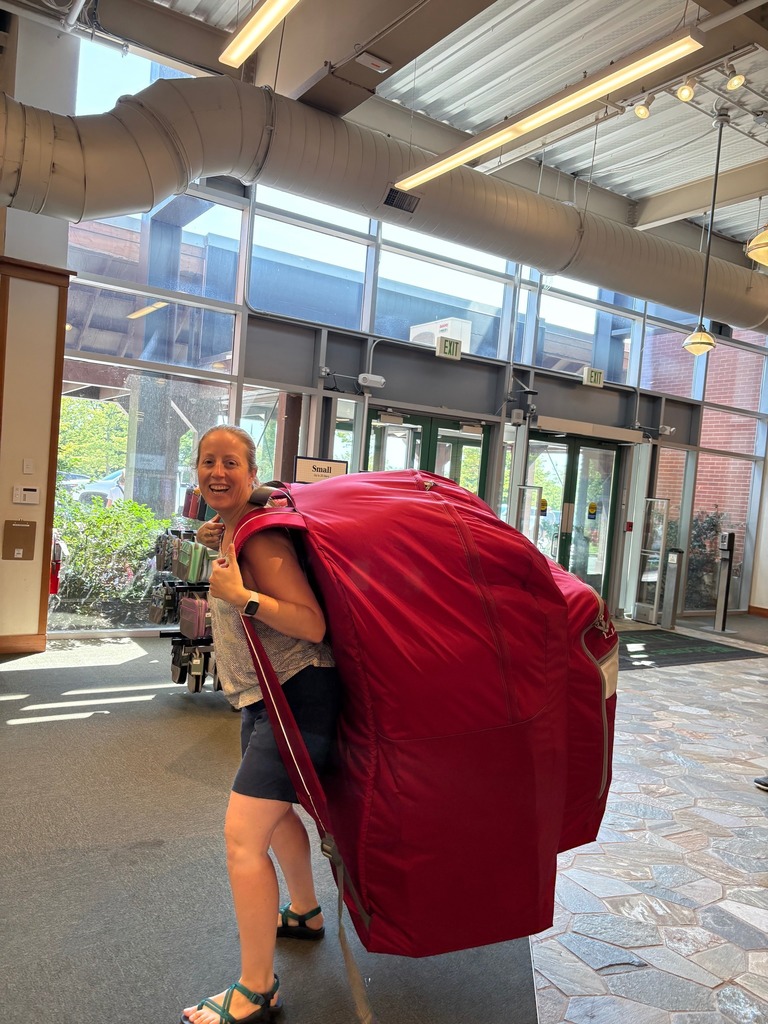 Jess holding a backpack that is bigger than her