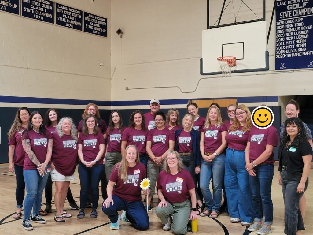 Albany Community School staff wearing their ACS shirts and posing in the gym at LR