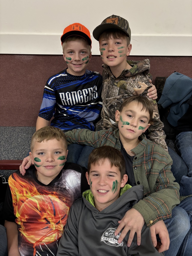 five 5th grade boys with face paint on their face posing on the bleachers