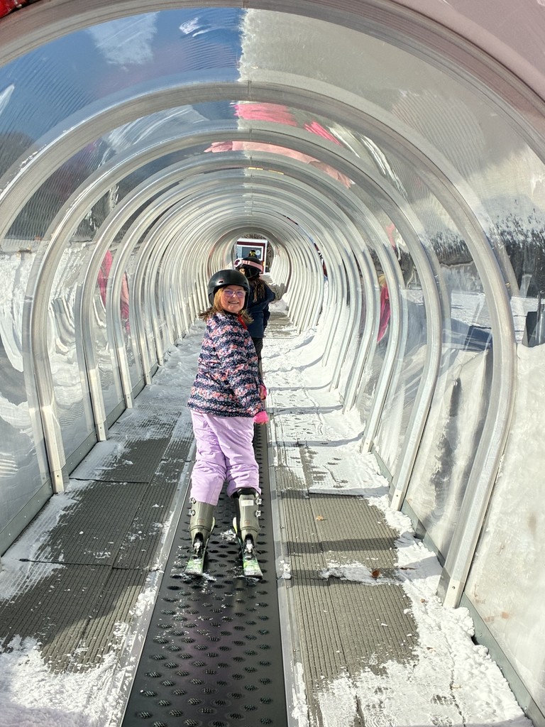 A beginner skier on the magic carpet smiling away