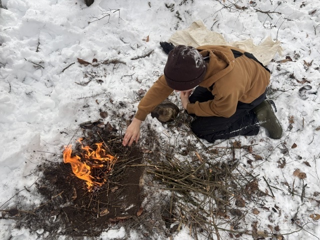 A student building a fire in the snow