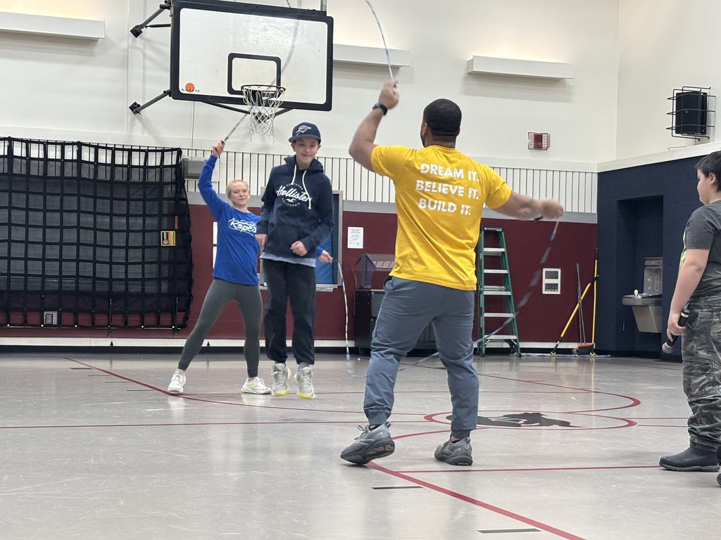 A 7th grade student jumps while Nick and Kaylee from Learnin' the Ropes uses their jump ropes with him