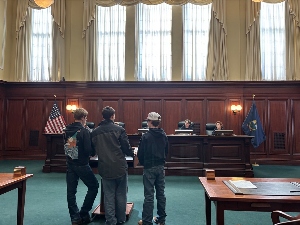 Three 8th grade boys present their case to the "justices" of the supreme court