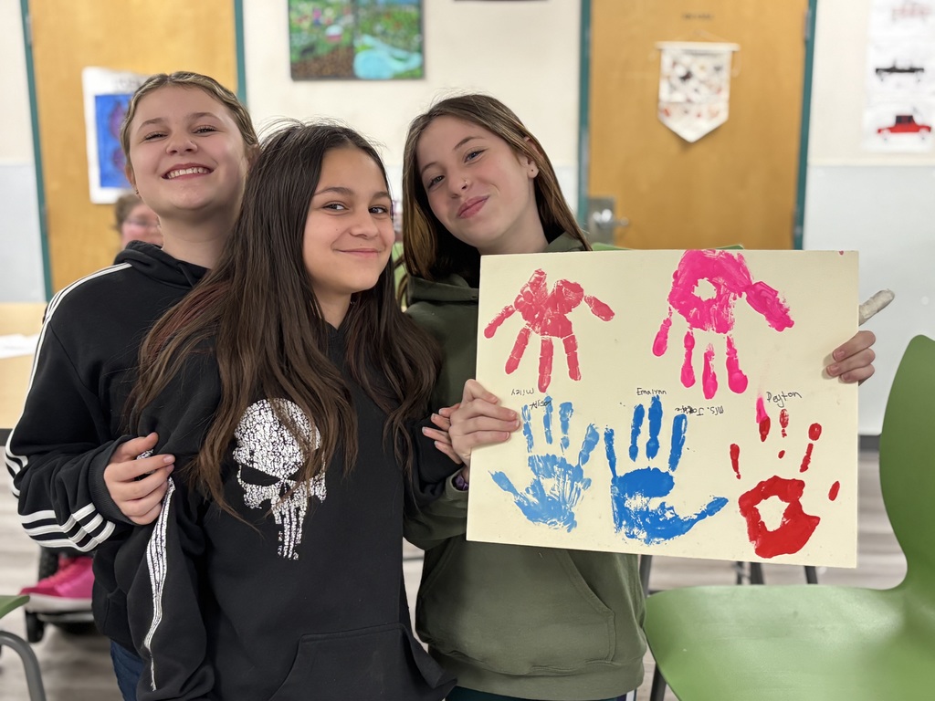 two 6th grades students and one 7th grade girl show off their painting in Art 