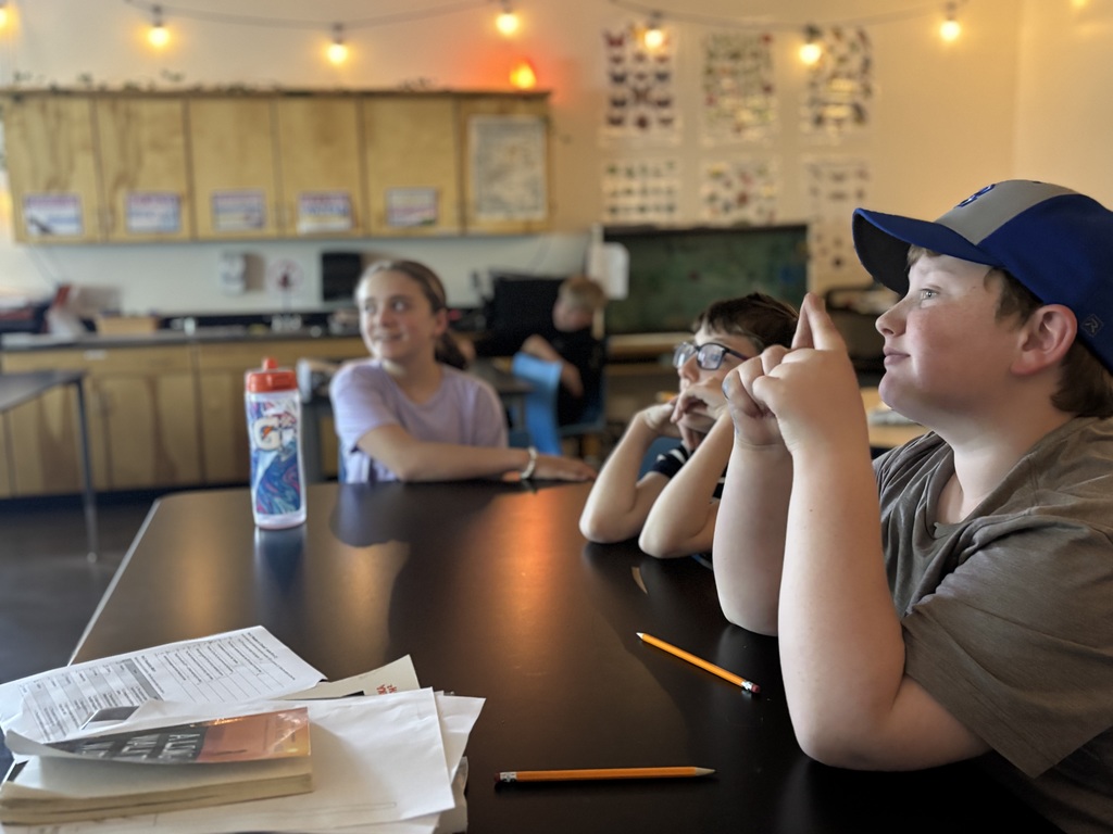 Three 6th graders are sitting at table in science